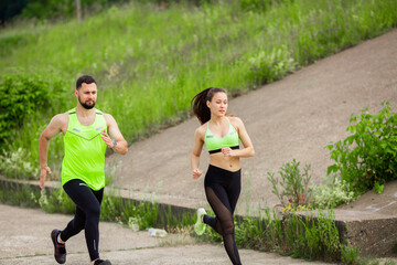 Athletic girl and man in stylish sportswear run in nature, photo for blog and ad of sport and healthy lifestyle