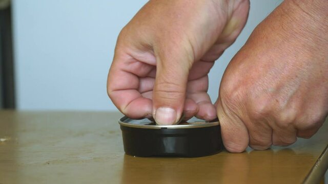 A man opens a can of canned fish