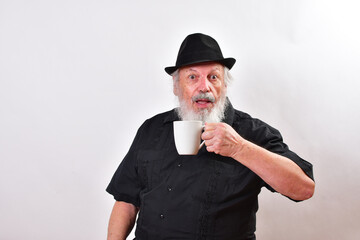 Happy man holding a coffee mug.  Smiling old man with a coffee cup . Delighted hipster holding a...