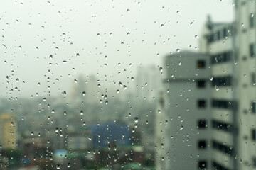 Rain drops on window's glass is viewing the city skyline.