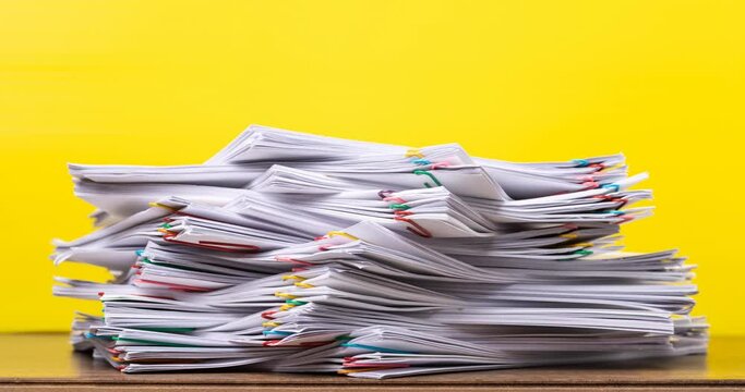 4K Stop of motion stack overload document report paper with paperclip place increase on yellow background, business and education concept footage paperless used. 