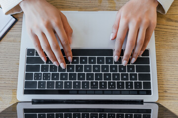 Fototapeta na wymiar top view of woman typing on laptop keyboard in office