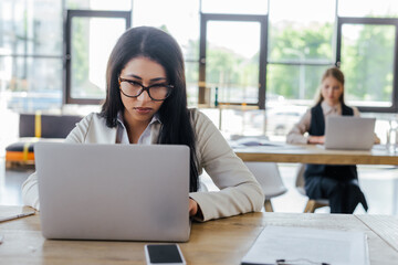Obraz premium selective focus of businesswoman working near colleague in office