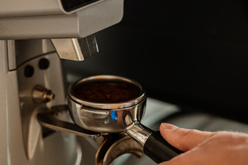 Closeup of barista grinding coffee. Professional barista working makeing coffee with coffee machine. Hot pouring drink concept. Toned picture