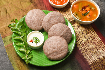 Ragi Idly, finger millet Idli, Sambar, coconut chutney healthy home made breakfast dish Kerala, Karnataka, India. steam cooked finger millet batter. Top view South Indian food dark black background.