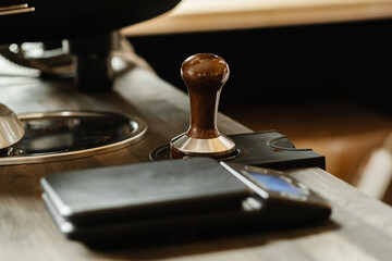 Fototapeta na wymiar Portafilter and coffee tamper making an espresso coffee. Professional barista working makeing coffee with coffee machine. Hot pouring drink concept. Toned picture