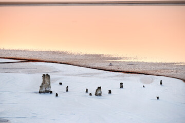 Sunset on the pink lake. Columns in salt crystals in white salt and pink water.