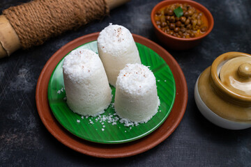 Popular South Indian breakfast puttu / pittu made of white rice flour and coconut in a bamboo mould, with banana, Kerala, India. Bamboo puttu prepared in the bamboo utensil. 