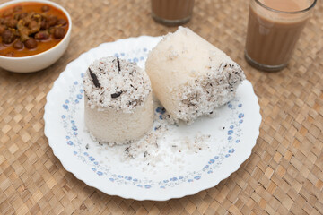 Popular South Indian breakfast puttu / pittu made of white rice flour and coconut in a bamboo mould, with banana, Kerala, India. Bamboo puttu prepared in the bamboo utensil. 