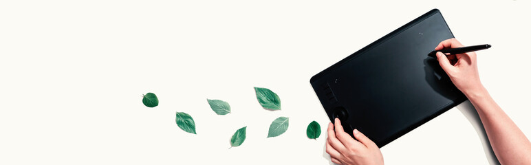 Graphic pen tablet with green leaves - flat lay
