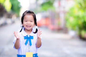 Kindergarten students wearing blue and white school uniform, standing ovation, happy to go to school. Sweet smile on morning of semester opening day. Asian child knit braids on both sides. 3 years old