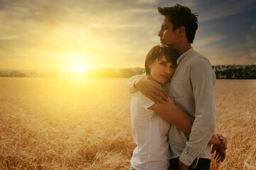 portrait of a couple hugging in a wheat field under a sunset