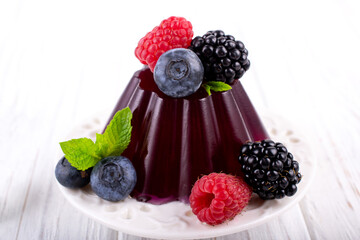 Sweet dessert jelly pudding with berries raspberries blackberries blueberries on white plate