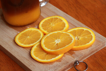 Orange slice and orange juice in a glass place on a wooden chopping block.