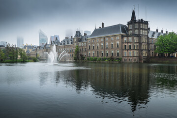 Binnenhof palace, place of Parliament in The Hague, Netherlands mirrored in the Hofvijver on a foggy day. Left the museum Mauritshuis