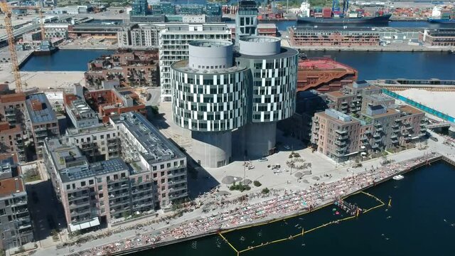 Aerial over harbour bath in Copenhagen showing Portland towers and people tanning at Nordhavn Sandkaj