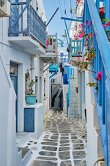 Picturesque scenic narrow Greek streets with traditional whitewashed houses with blue doors windows of Mykonos town in famous tourist attraction Mykonos island, Greece - obrazy, fototapety, plakaty
