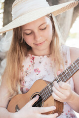 Eine junge Frau mit Hut spielt Ukulele