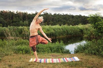 Handsome fit man doing yoga at the park