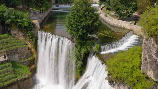 Jajce Waterfall in Bosnia and Herzegovina with tourists posing for pictures on the lookouts, Aerial flyover shot