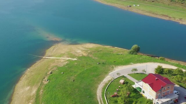 Rama Lake in Bosnia and Herzegovina with Mediteran Caffe Restaurant near the shore, Aerial flyover shot