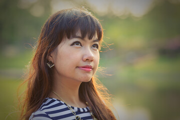 Young beautiful Asian woman at the park thinking