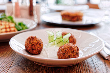 Zucchini croquettes and other dishes on restaurant table, toned