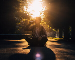 A man is sitting on the road and drinking coffee.