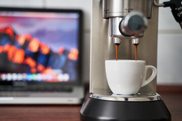 Espresso läuft von einer Siebträgermaschine in eine Espresso Tasse. Unscharfer Hintergrund....
