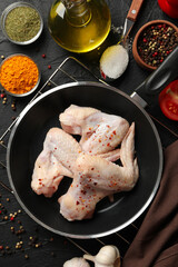 Raw chicken meat and spices on black background, top view. Cooking chicken