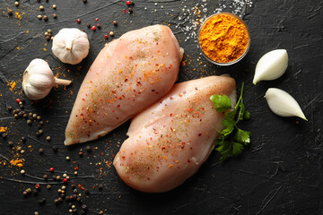 Raw chicken meat and spices on black background, top view. Cooking chicken