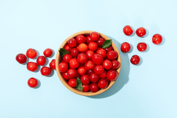 Bowl with fresh red cherry on blue background, top view