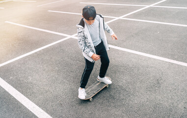 Teenager skateboarder boy with a skateboard on asphalt playground doing tricks. Youth generation Freetime spending concept image.