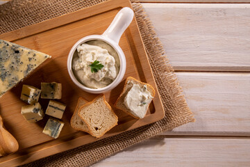 Obraz na płótnie Canvas Blue cheese cream and toasted bread on wood background. Pate de gorgonzola in Brazil.