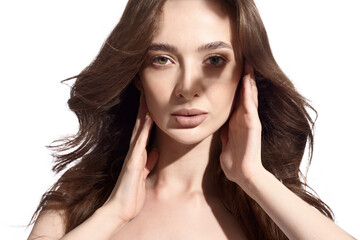 Beautiful young brunette with natural make-up and silk long hair on a white background. Shadow on the face. Woman looking at camera. Isolated over white background.
