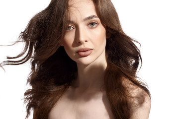 Beautiful young brunette with natural make-up and silk long hair on a white background. Shadow on the face. Woman looking at camera. Isolated over white background.