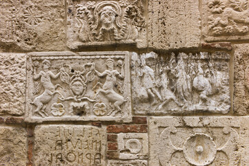 Etruscan and Roman stone carving reliefs on a wall of Palazzo Bucelli in Montepulciano, Tuscany, Italy