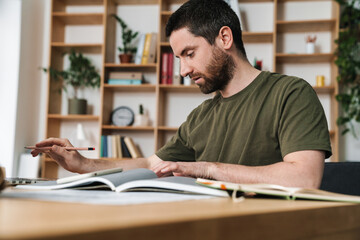 Obraz premium Photo of focused man making down notes and using laptop while working