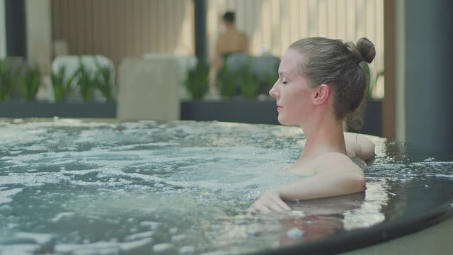 Woman relaxing in hot tube, Resting in whirlpool water in wellness spa resort.