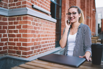 Smiling successful female copywriter casual dressed communicating over mobile phone with friend...