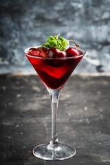 Cherry cocktail in martini glass with berries and mint leaves. Selective focus. Shallow depth of field.
