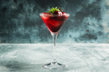 Cherry cocktail in martini glass with berries and mint leaves. Selective focus. Shallow depth of field.
