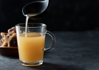 Homemade Beef Bone Broth in Glass Storage Jar on a black background with copy space