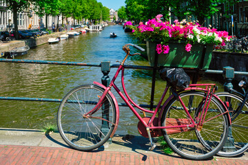 Fototapeta na wymiar Typical Amsterdam view - Amsterdam canal with boats and parked bicycles on a bridge with flowers. Amsterdam, Netherlands