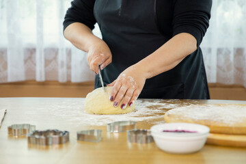 Obraz na płótnie Canvas Female baker cooking bread, close up of woman hands mom grandma mother slicing raw dough ball covered with flour on wooden table. Baking concept, pastry products, cooking with love, homemade