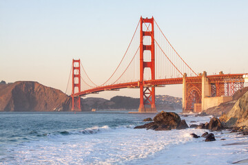 The evening view of Golden Gate Bridge with the waves of Atlantic Ocean in the foreground