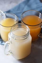 Homemade Beef Bone Broth in Glasses on a gray concrete background, close up