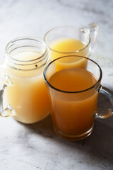 Homemade Beef Bone Broth in Glasses on a gray concrete background, close up