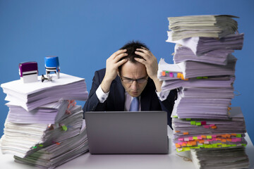sad depressed exhausted office worker wrapping his hands around his head.