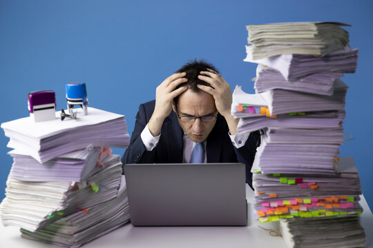 sad depressed exhausted office worker wrapping his hands around his head.